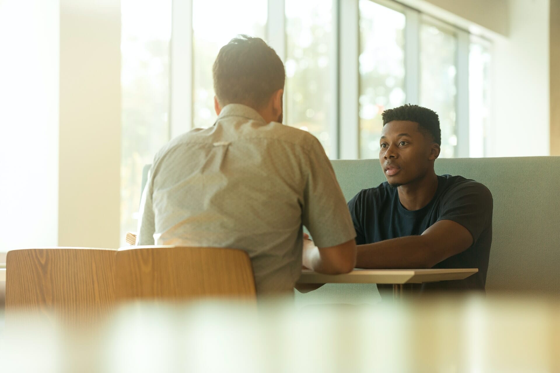 Dos jóvenes sentados frente a una mesa mantienen una conversación crucial.