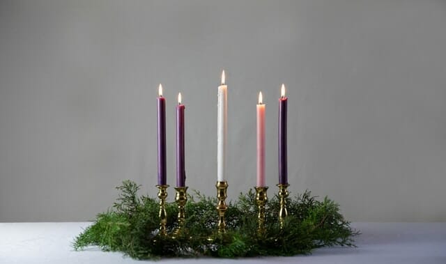 An advent wreath on a table with one central candle, and four smaller candles on either side. These five candles represent the five weeks in the lead up to Christmas.